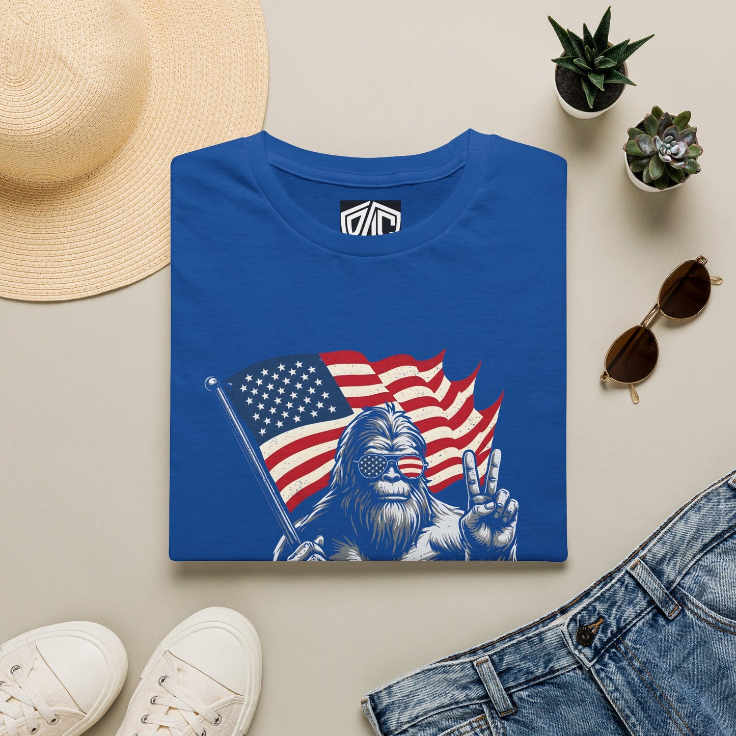 T-Shirt — Patriotic Bigfoot Holding American Flag "MERICA" Graphic